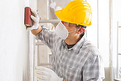 Pessoa lixando parede antes de pintar